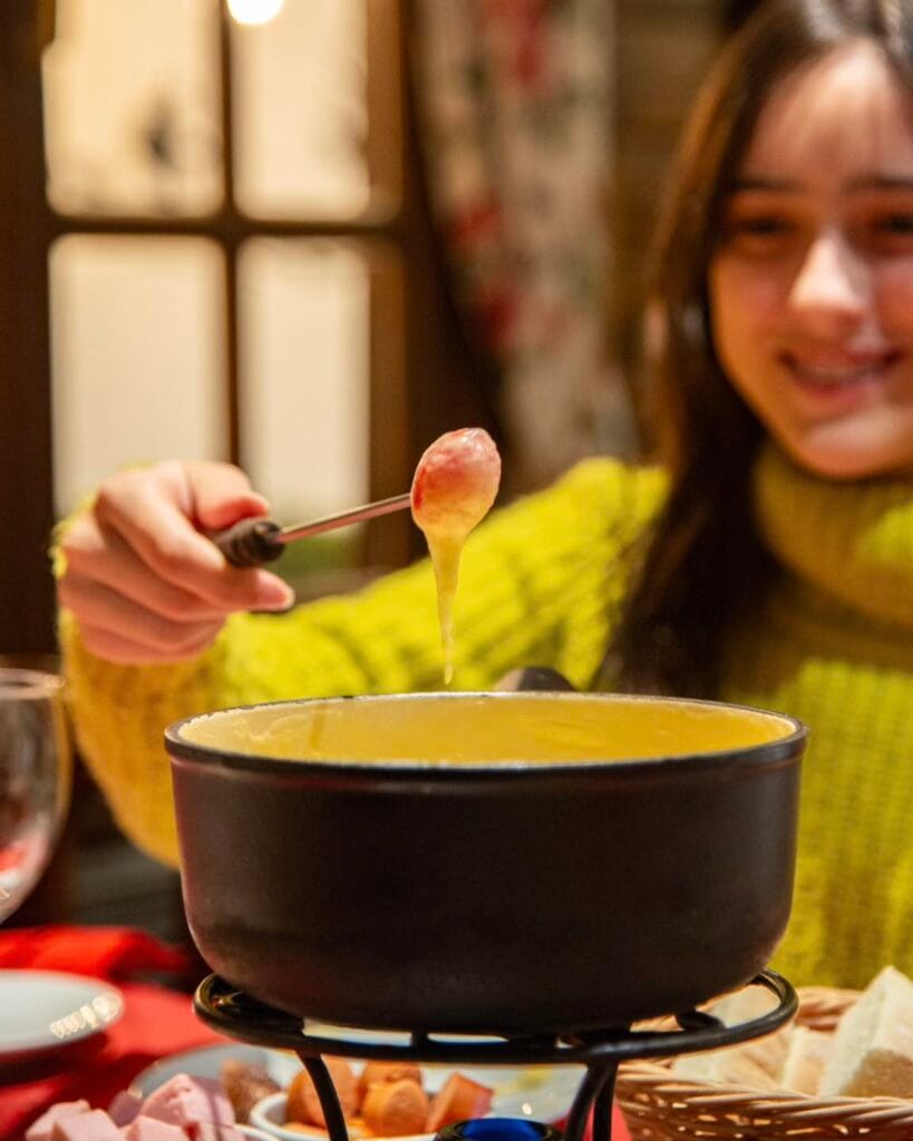 Fondue de queijo no restaurante La Marmite em Bariloche, com fio de queijo derretido no garfo