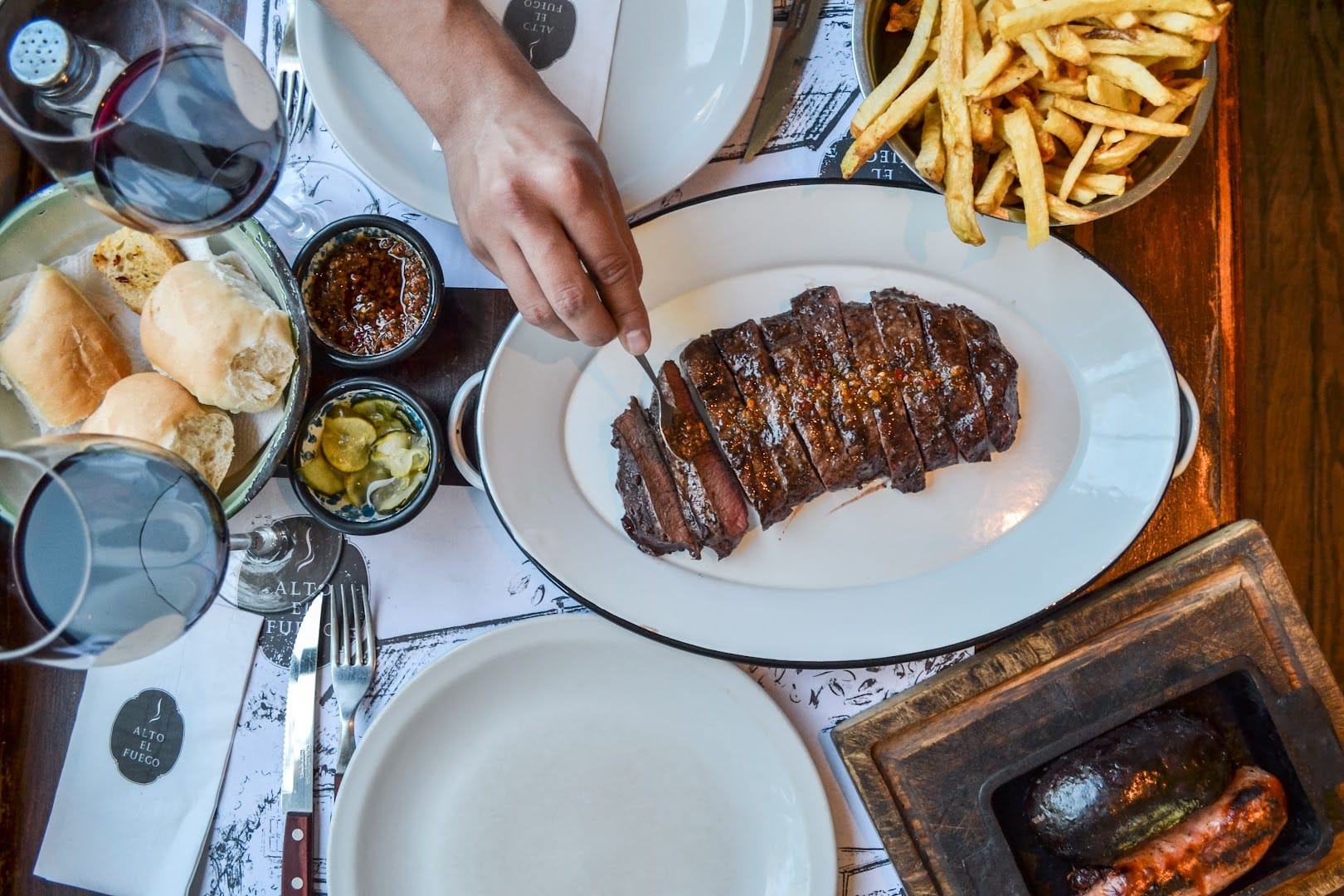 Mesa completa de parrilla argentina no Alto El Fuego em Bariloche: bife, fritas, morcilla e vinho