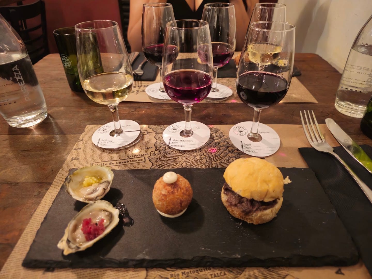 Tábua de petiscos com taças de vinho no Bocanáriz em Santiago